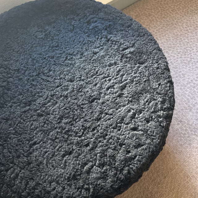 This stylish accent chair features a sculptural curved wooden back and armrest, paired with a plush, textured black boucle...