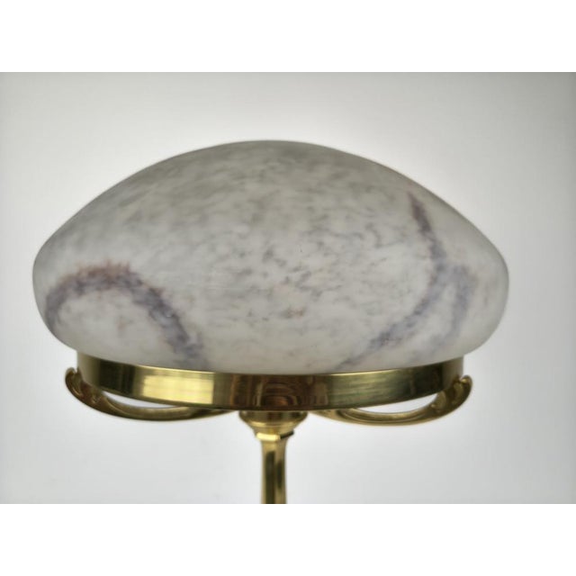 Elegant statement table lamp with a polished brass base and a beautiful marbled glass shade. The sculptural dome form,...
