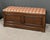 Solid oak storage bench offering spacious storage space and comfortable seating thanks to its padded cushion in orange...