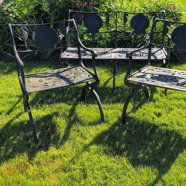 Cast aluminum, black painted surface. Two-seat settee and pair of armchairs with seahorse and seashell motif backrests....