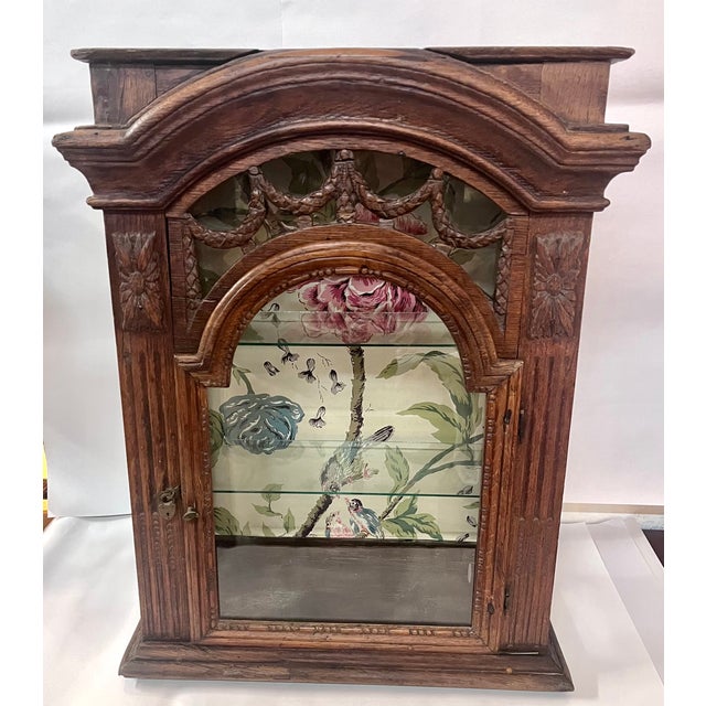 Imported from France. Ornate arched top curio cabinet with glass front, sides, and shelves. Intricately carved garland...