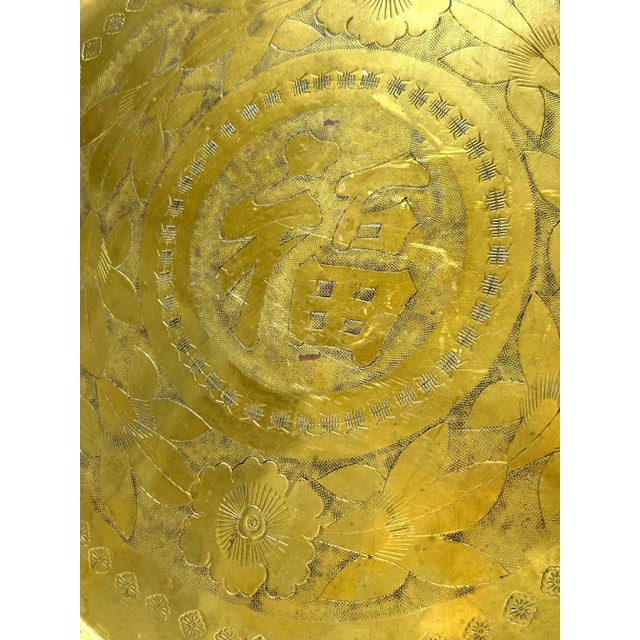 A vintage round brass tray with floral engraving surrounding a central decorative medallion. Repeating small motifs...