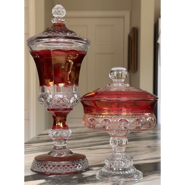 Presenting a pair of excellent condition lusterware ruby red flash cut to clear lidded candy dishes. The apothecary is by...