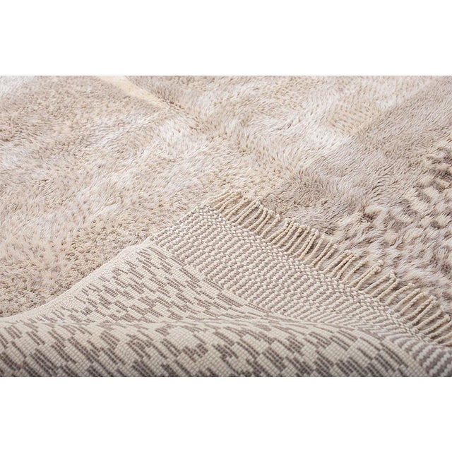 Softness you can see: a surface of shifting tones, like morning light on raw stone. An ivory ground mingles with light...