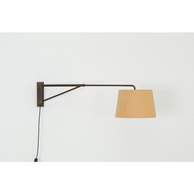 A minimalist Art Deco swing-arm wall lamp dating from the 1920s. The fixture is constructed from brass and features a...