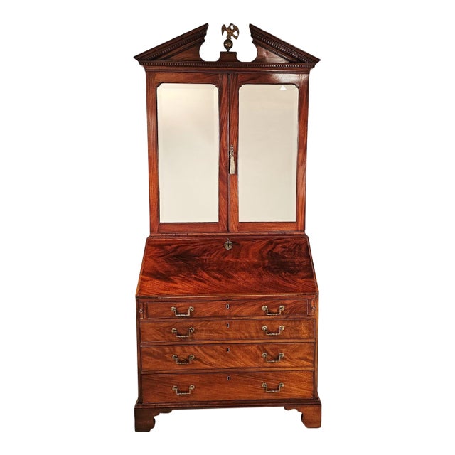 A George III secretary bookcase, England, 18th century. The secretary has a broken pediment and mirrored doors.