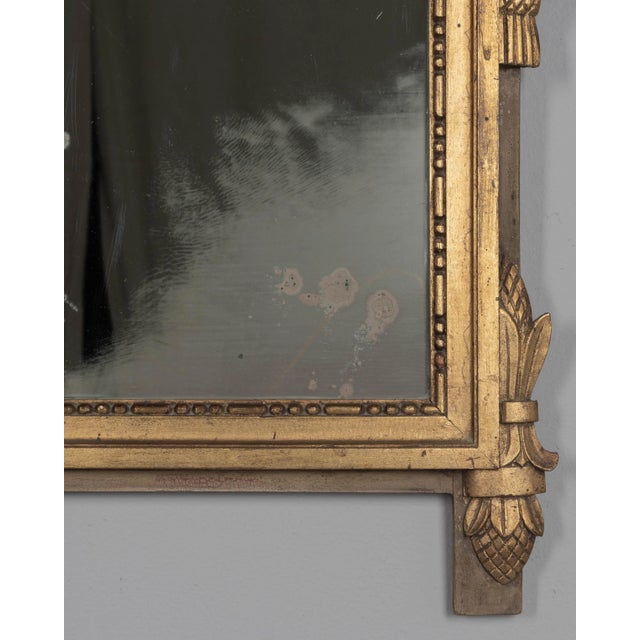 A Louis XVI style French Provençal giltwood mirror. Hand carved crest with ribbons, garlands, torch and quiver. Gilt is in...