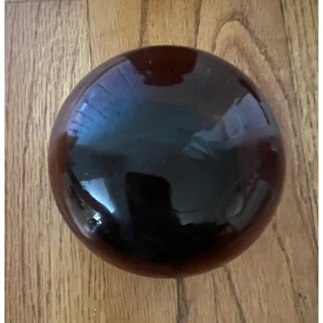 Handmade amber glass apothecary-style jar with a rounded, dome-shaped glass lid. There's a dark rubber or plastic seal...