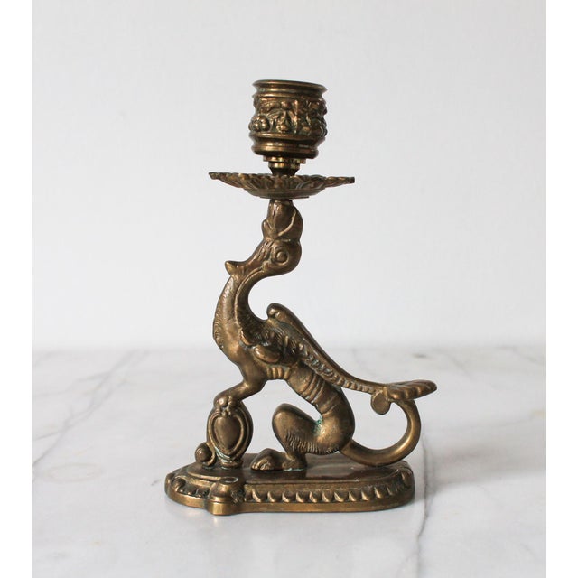 Vintage Victorian-style brass griffin candlestick holder. It features an ornate mythological creature with a curled tail...