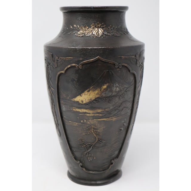 An intricately decorated Japanese bronze vase bringing together a Mount Fuji landscape, a dramatic figural dragon scene...