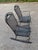 A pair of matching black diamond mesh wrought iron rocking chairs with a floral design on back and arms in the style of...