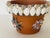 4-5” Terracotta flower pot encrusted with sea shells arranged in 5 different flower patterns.