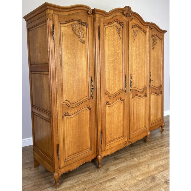 An elegant Vintage French Louis wardrobe with an impressive four-door design, crafted in oak and displaying a warm natural...