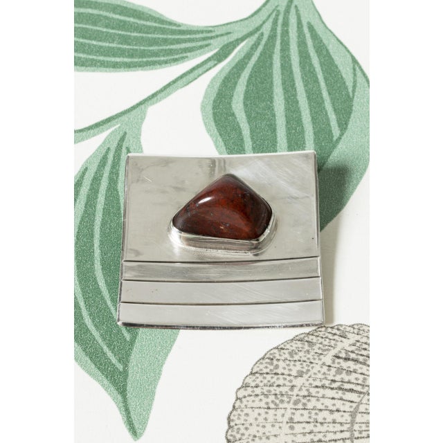 Cool, large brooch by Heikki Kaksonen, made from silver in a square form with embossed stripes. A smoothly tumbled jasper...
