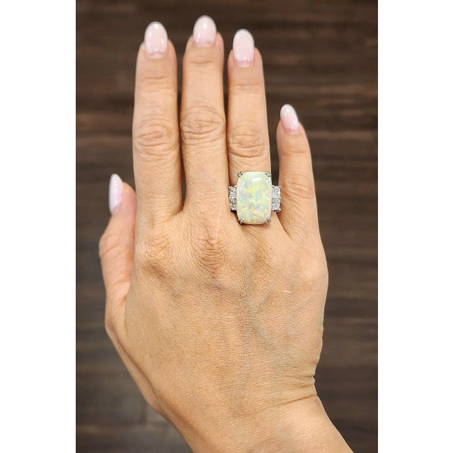 This exquisite ring is a true statement piece, showcasing a breathtaking 7.79 carat natural Australian Opal as its...