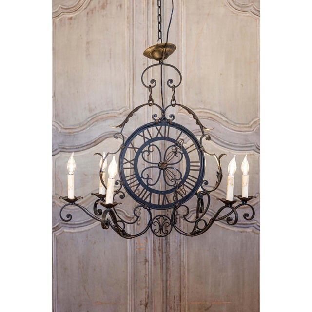 A French wrought-iron clock face chandelier from the 20th century with six scrolling arms and acanthus leaf motifs. This...