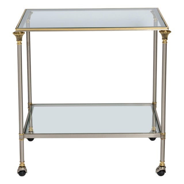 This is a is striking, minimalist French Hollywood Regency style two-tier rolling bar cart. Exhibiting the refined mixed-...