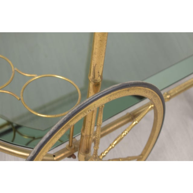 An elegant Italian bar cart from the 1970s, featuring a refined brass frame with a bamboo-effect pattern and smoked...