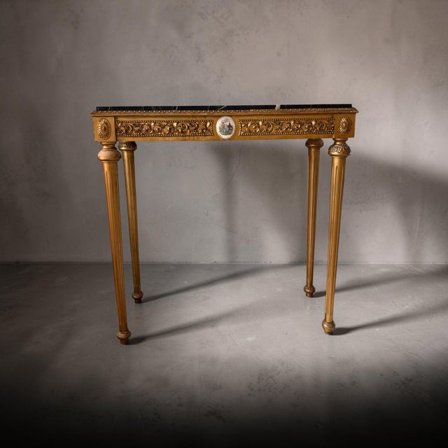 Exquisite French gilt wood console table with black marble top in the style of Luis XVI. The gilt wood features beautiful...