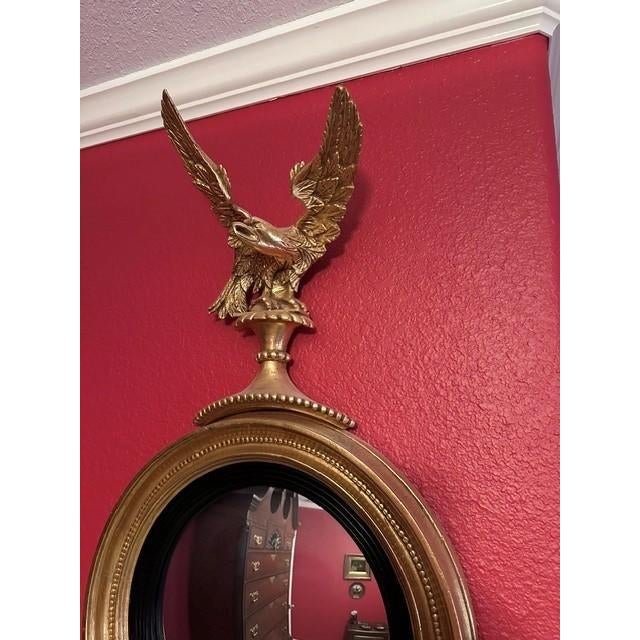 This decorative wall mirror features a classic Federal style design, characterized by a gold finished eagle crest perched...