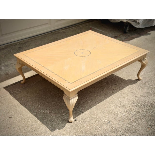 A beautifully crafted vintage coffee table featuring a sophisticated pickled cherry finish, intricate inlaid top, and...
