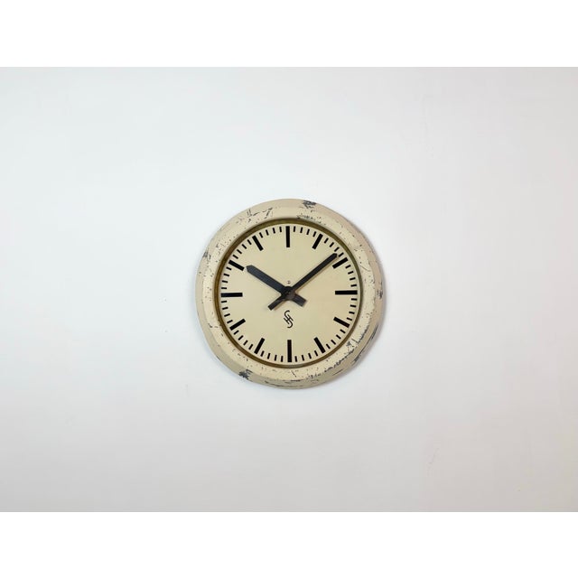 This wall clock was produced by Siemens in Germany during the 1950s. It features a beige metal frame, a metal dial and a...