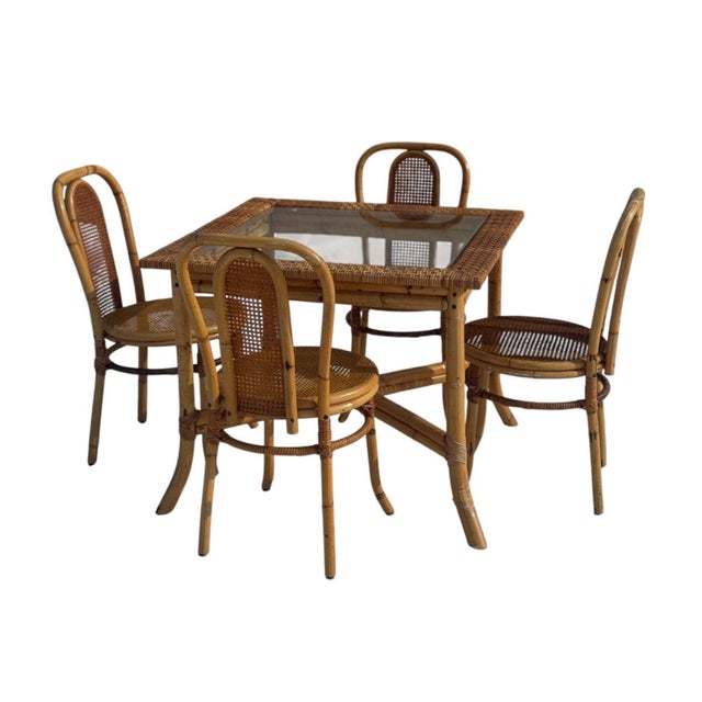 Vintage rattan dining set dating to the 1970s–1980s, featuring a square rattan table with insert glass top and four...