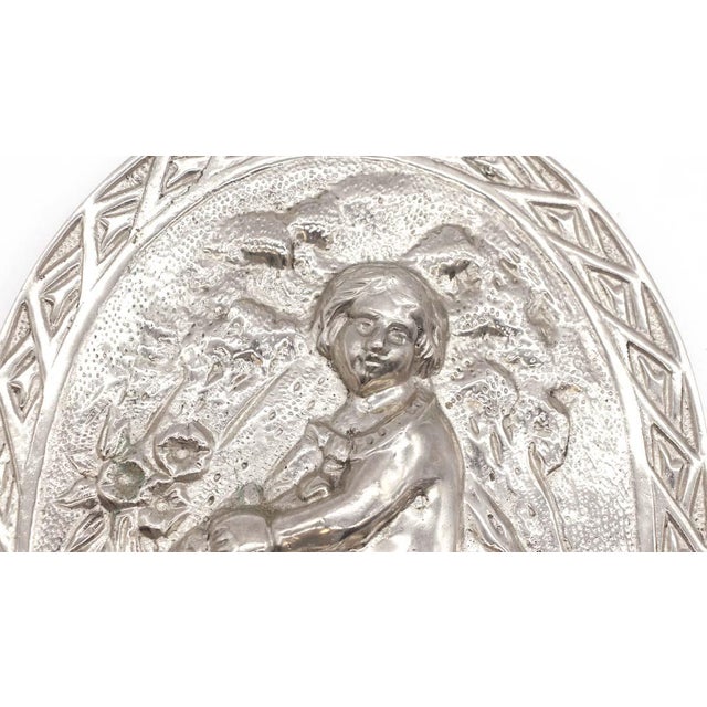 Solid cast aluminum oval wall relief with a floral design of a young child on horseback. Good condition with appropriate...