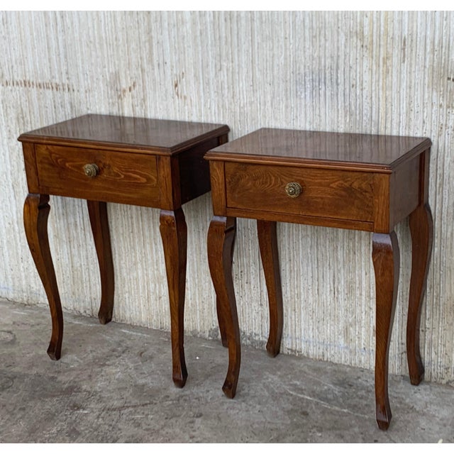 A pair of French Louis XV style walnut bedside tables from the early 20th century. This pair of French 'tables de chevet'...