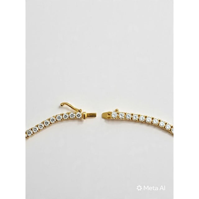 A timeless 14K yellow gold tennis necklace featuring 11.8 carats total weight of natural round brilliant-cut diamonds....