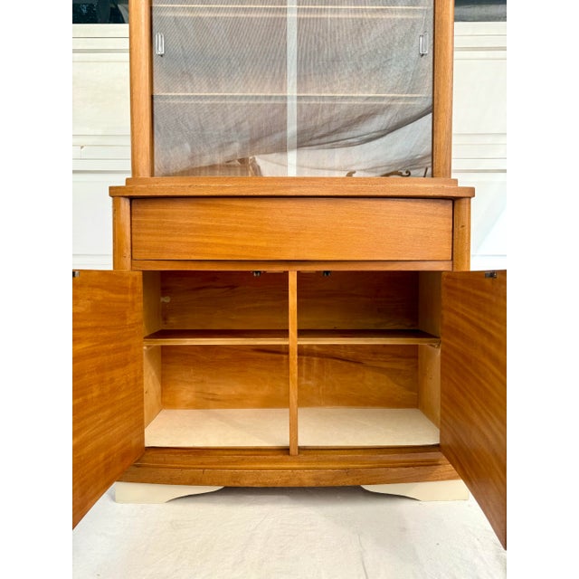 Here is a wonderful china cabinet from the mid-century featuring both open display areas and closed storage in a warm,...