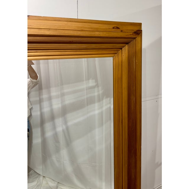 A clean and understated full-length mirror framed in natural pine, featuring an intricate and subtly profiled molding and...