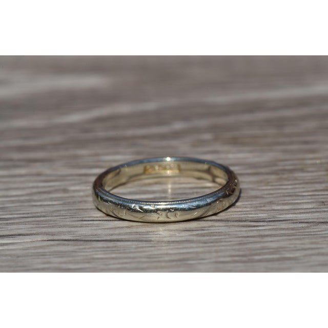 The El Monte: Antique White Gold Wedding Band. The band features a floral pattern slightly faded in the center with an...