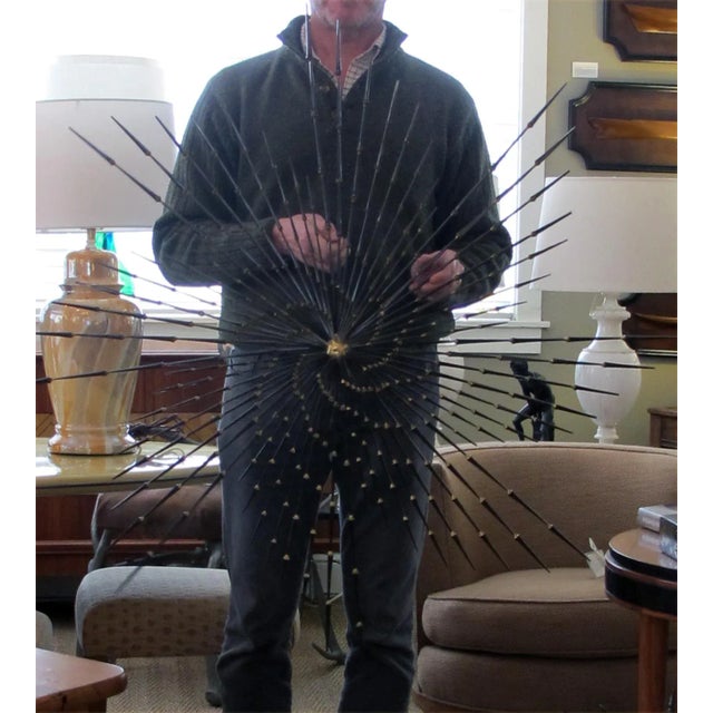 this explosive brutalist iron nail wall sculpture contrasting the cold black steel iron nails and the warm buffed-brass...