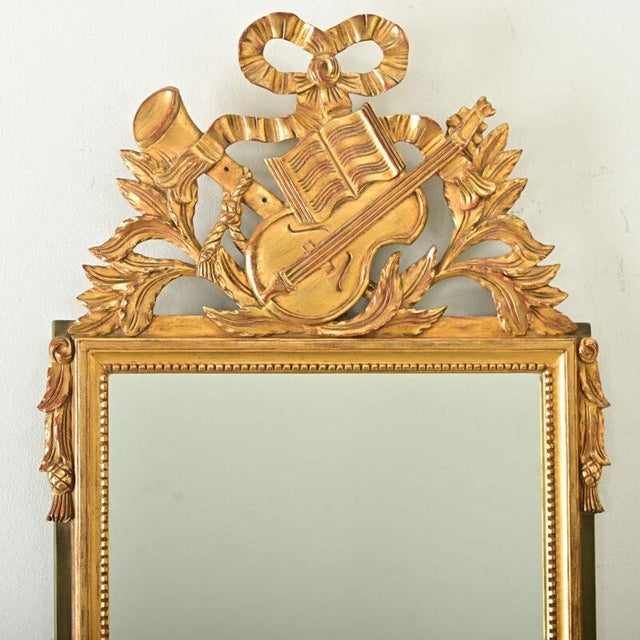 Dimensions: 33 ⅝” H x 19 ¾” W x 1 ½” D A charming music-themed giltwood mirror from France, circa 1870. Topping the piece...