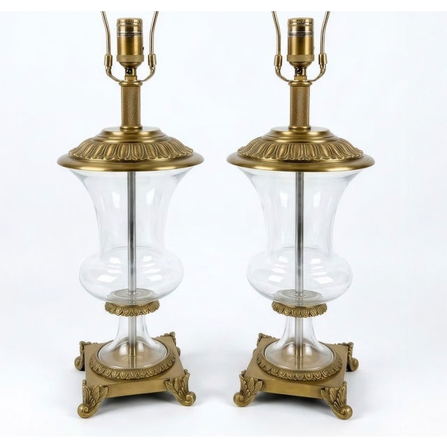A striking pair of vintage Neoclassical hurricane-style table lamps featuring clear, urn-shaped mouth-blown glass bodies...