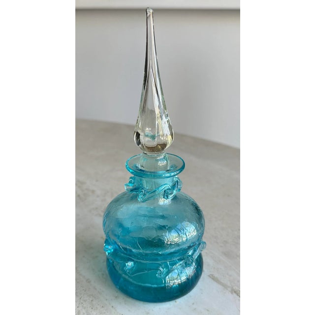 Heavy, blown glass bottle decorated around the rim and base in a beautiful turquoise ribbon of glass. Topped by a...