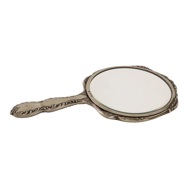 A beautiful round hand mirror with a beveled edge, made in France around the 1940s from silver-tone metal (*métal blanc*);...