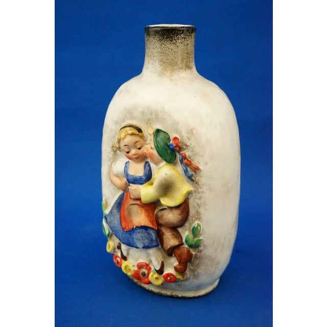 A delightful glazed ceramic bottle with a satin finish, featuring a central bas-relief decoration depicting a pair of...