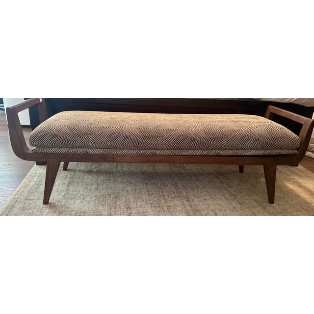 Arteriors “Santana” bench featuring a sculptural walnut wood base and upholstered seat in a refined herringbone textile....