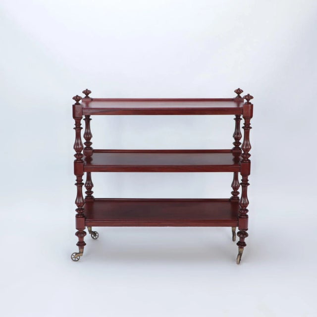 An English mahogany 19th Century three tier dessert on wheels having shaped and carved columns.