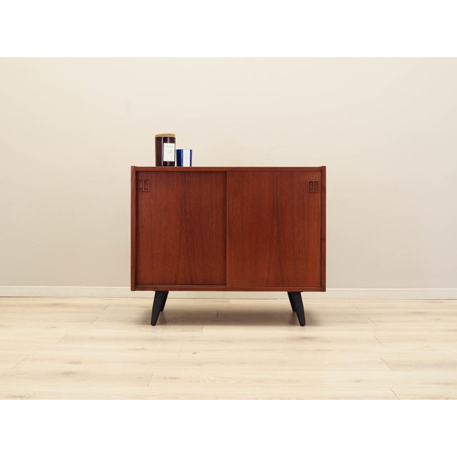 The cabinet was made in the 1970s, Danish production. The structure is covered with teak veneer. The legs are made of...