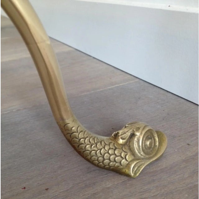 This coffee table with dolphin heads is made of brass with a black lacquered glass top. This is a French work by famous...