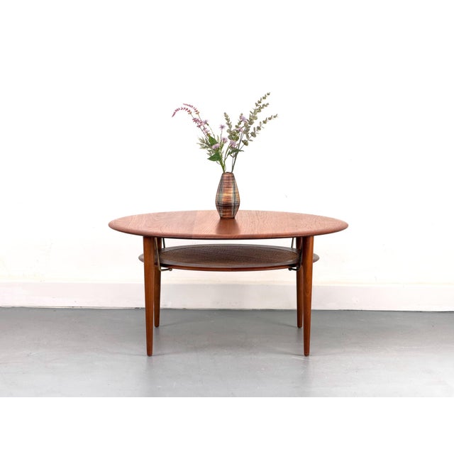 Iconic coffee table in solid teak by Peter Hvidt and Orla Mølgaard Nielsen for France & Søn. The removable woven shelf is...