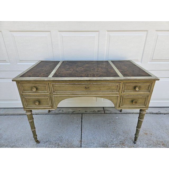 This Baker Furniture writing desk features a distressed light green and black finish and has five drawers. The desk has...