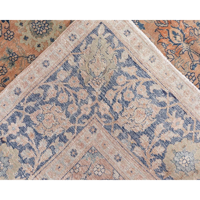 An early 20th century Persian Tabriz rug, the dusty rust field with an allover trellis design of palmettes and flowering...
