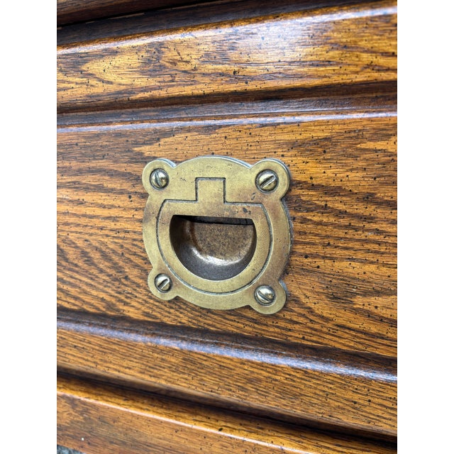 Oak Campaign Style Nightstands featuring dark wood grain, recessed brass-finish hardware, and a dark top surface....