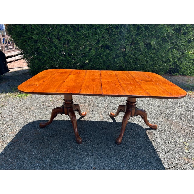 Stately and versatile warm walnut dining table having gorgeous grain and visible old world nailheads on top, with two...