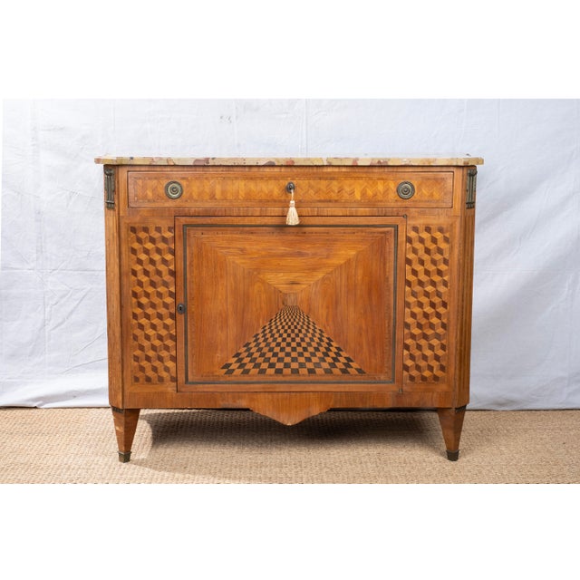An antique commode, early 19th century, French. Empire / Neoclassical style featuring intricate parquetry, original brass...