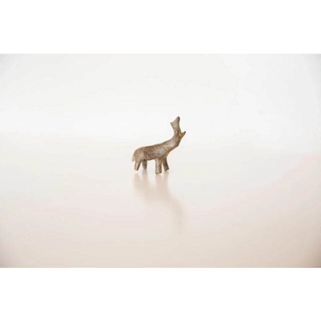 :: Vintage handmade bronze sculpture of a mini elephant with its trunk facing upwards. Circa mid 20th century and possibly...